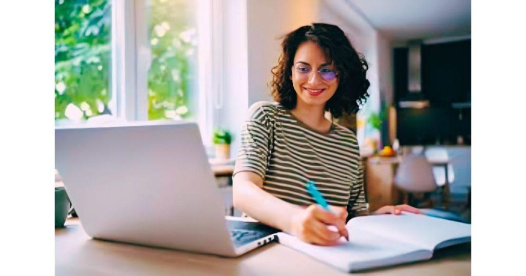A college student working on a sleek laptop in a bright study environment.